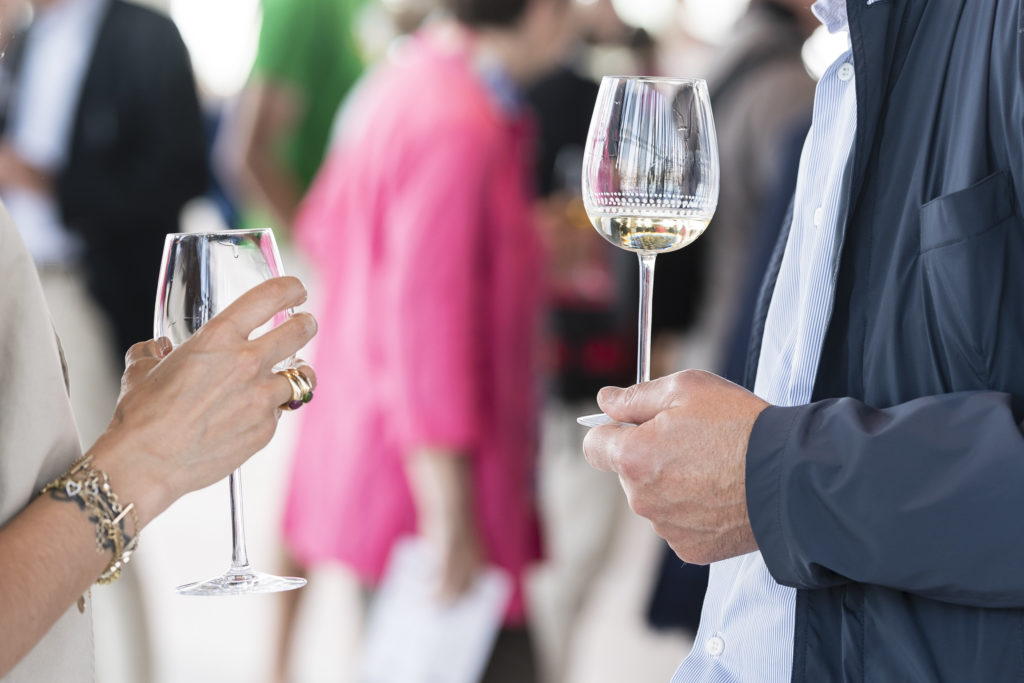 deux personnes face à face qui tiennent un verre de vin blanc